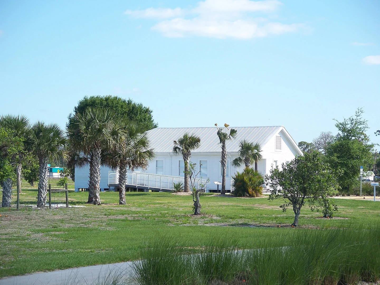 White wooden building surrounded by palms and lawn at Roberts Ranch in Immokalee