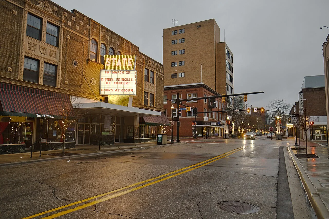 The illuminated State Theatre marquee in Kalamazoo beside a rain-darkened street.