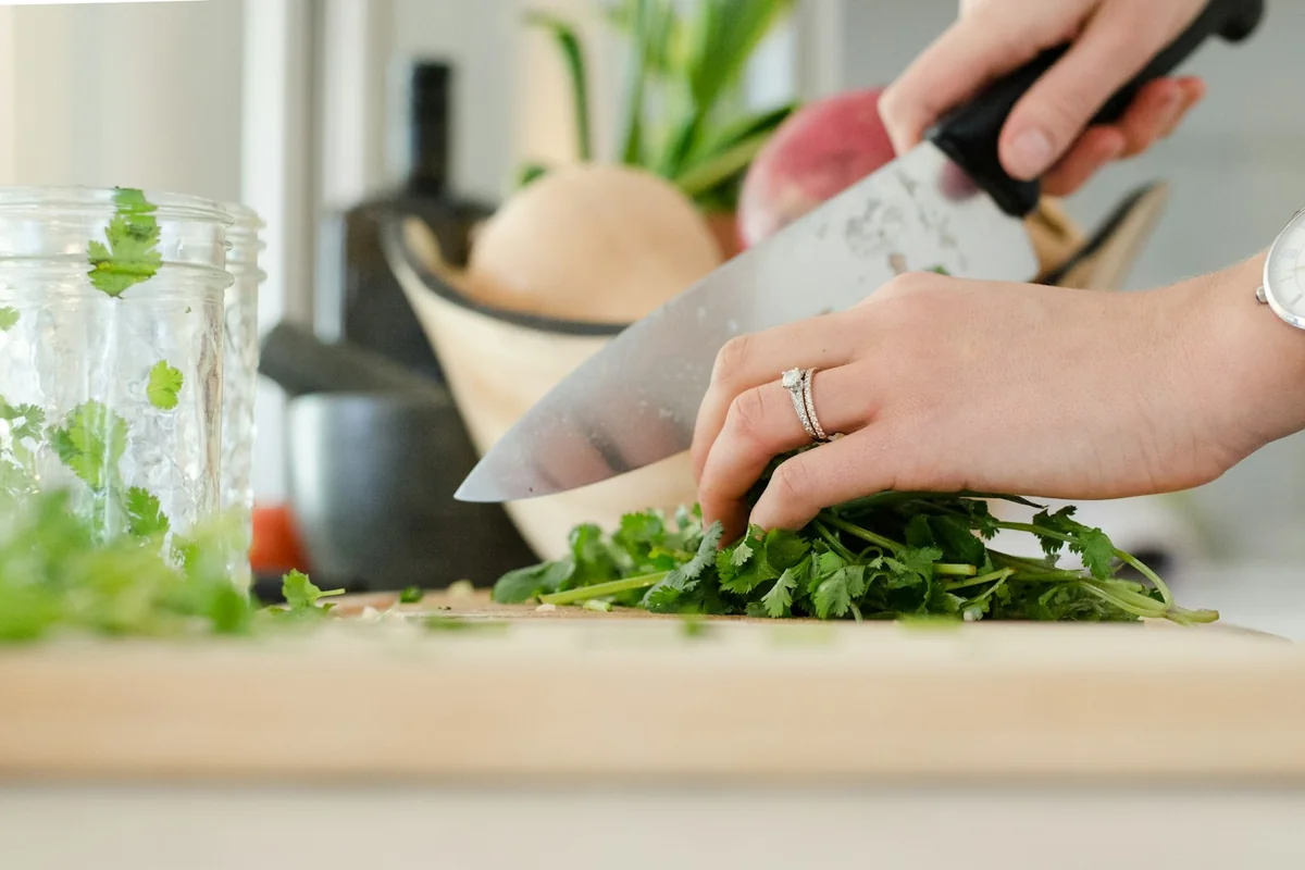 Hands chopping fresh herbs on a cutting board